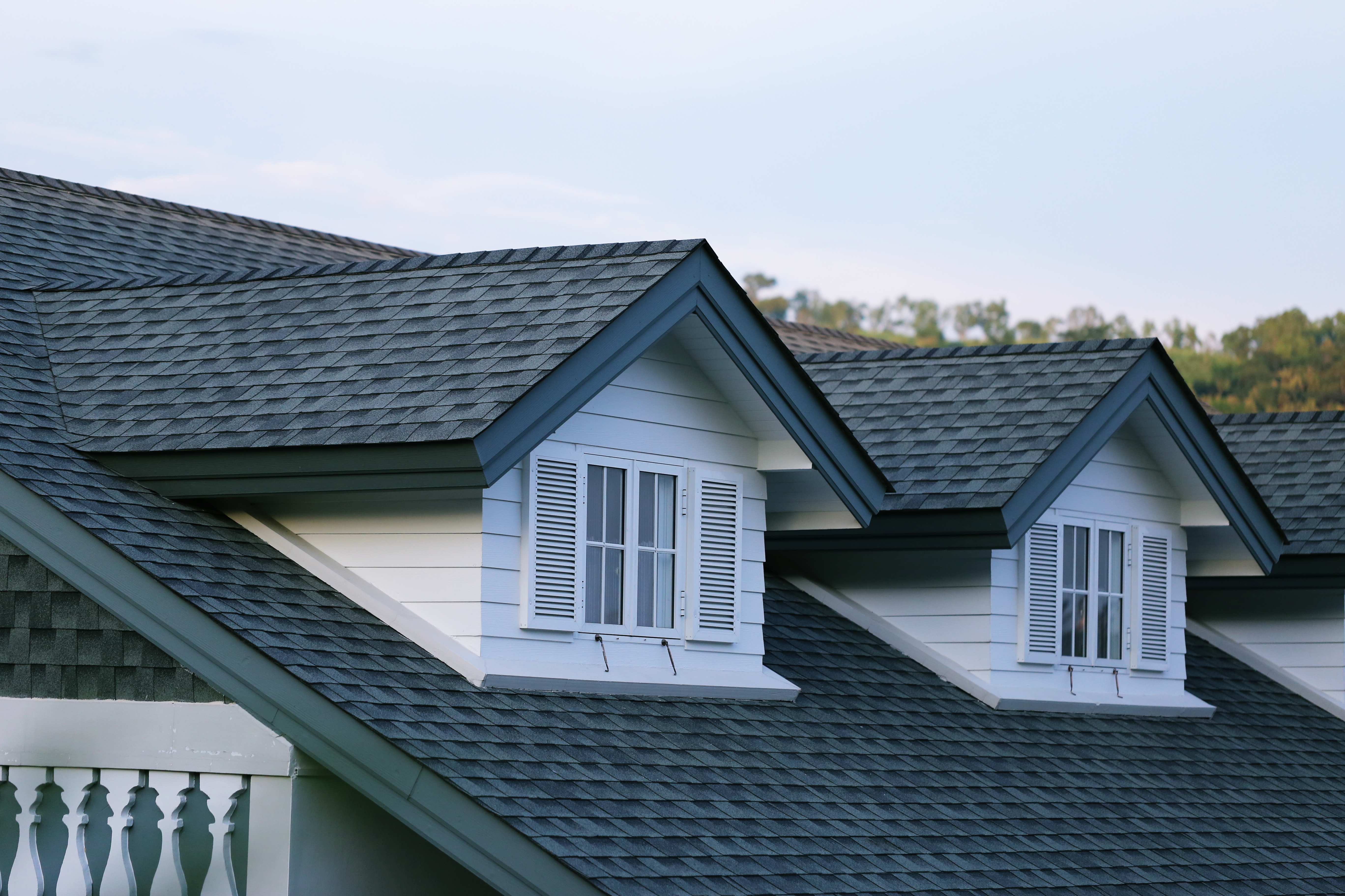 Dormer windows with dark architectural shingles and white siding